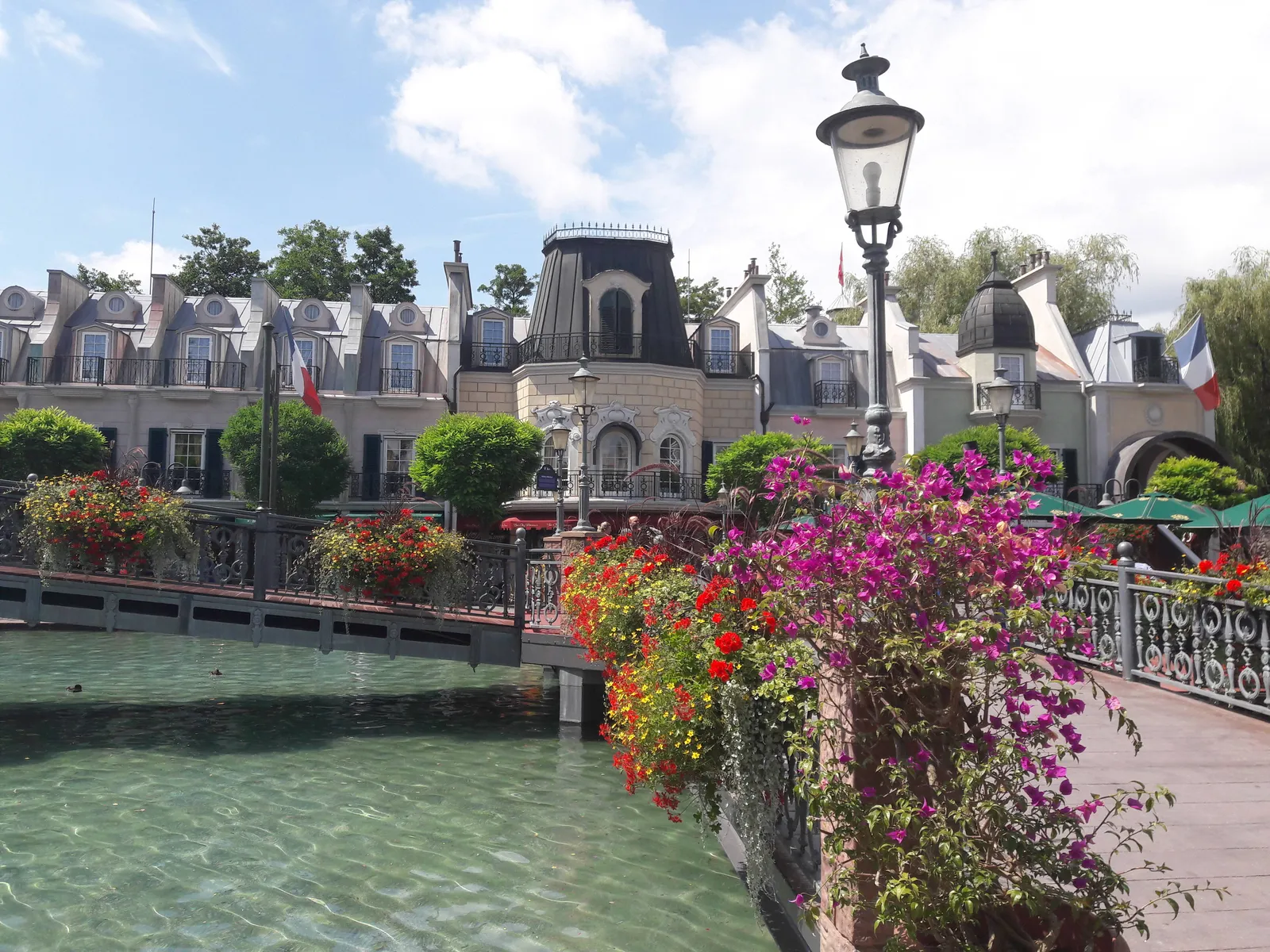 Kanal mit Bougainvilleen vor Fassaden im französischen Stil